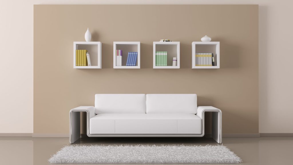A white couch sitting in front of four wall mounted shelves.