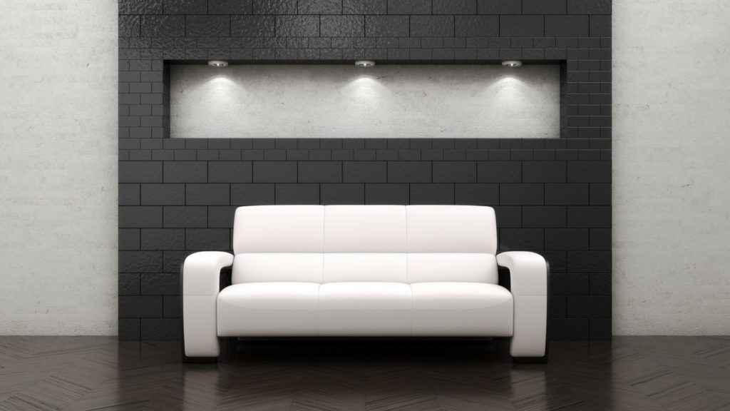 A white couch in front of a black wall.